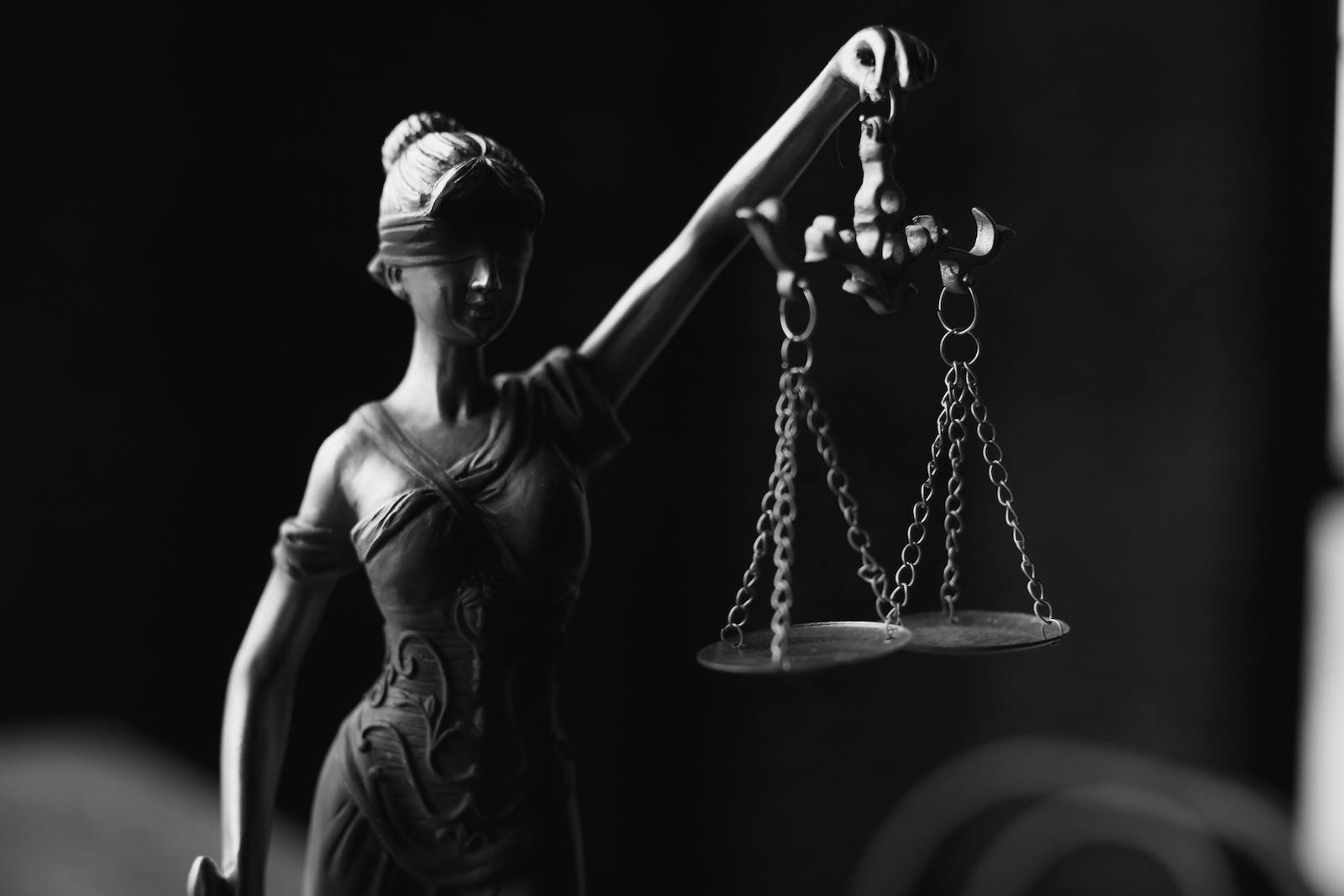 A black and white photo of statue of holding the scales of justice.