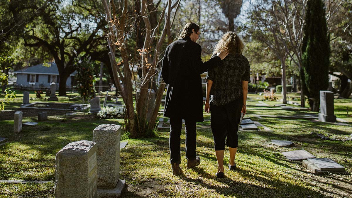 Grieving family members exit a cemetery